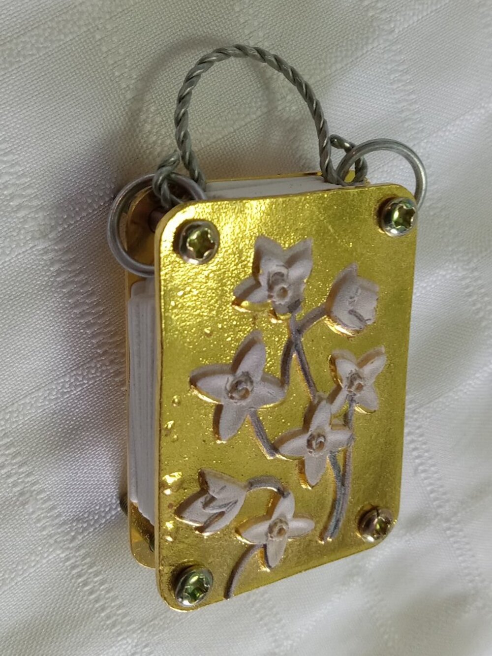 Pretty metal engraved little flower press in gold tones with a hook